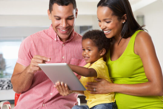 AA parents with young boy looking at ipad