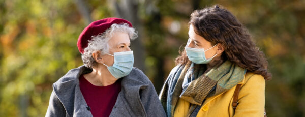 Elderly woman and young woman with masks walking